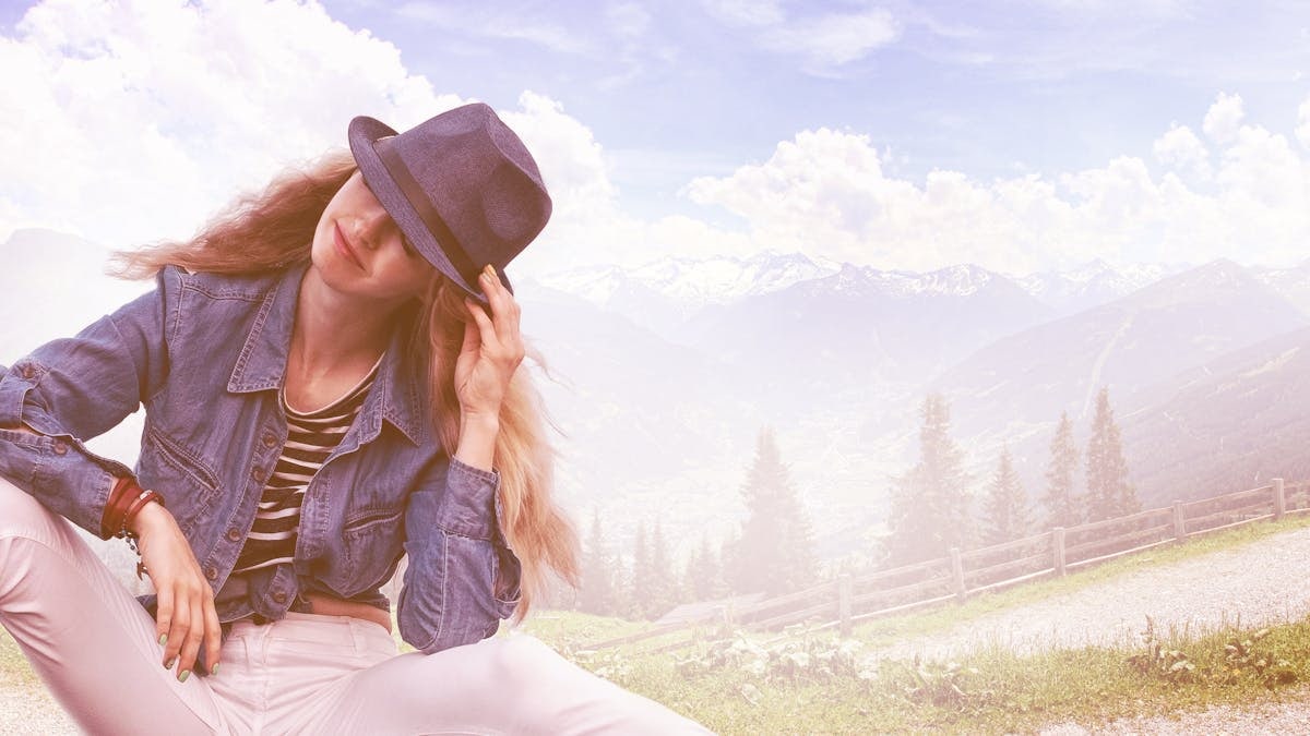 A woman in a casual chic outfit poses outdoors with a stunning mountain backdrop.