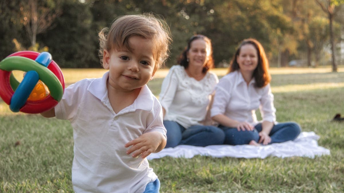 A joyful family enjoying a picnic in the park with a playful toddler in the foreground.